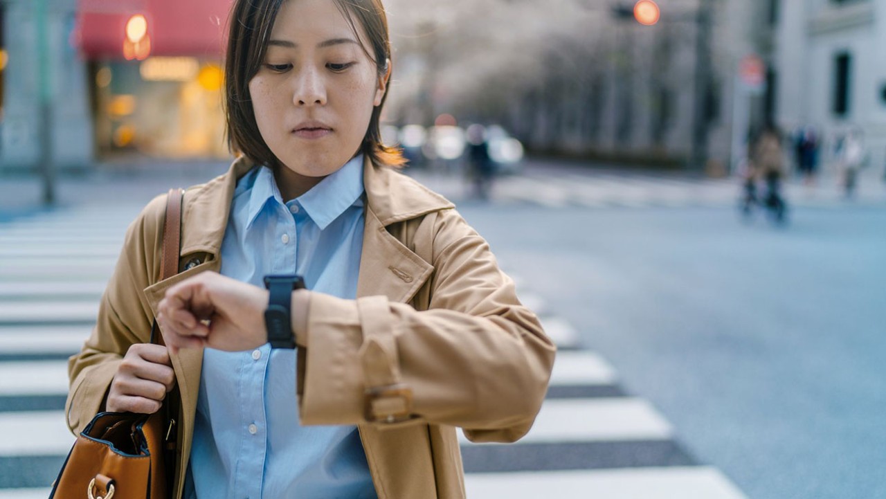 Woman walking across the street looking at her watch