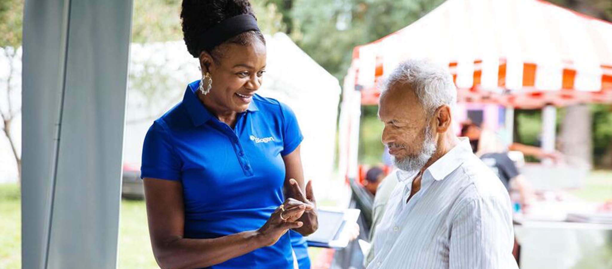 A Biogen employee shares education materials about diseases with a person.