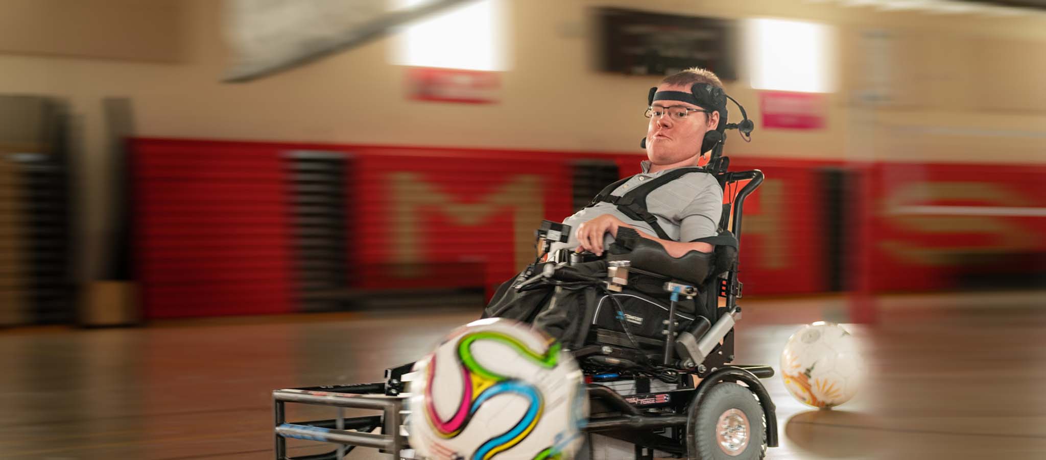 Nathan in a gymnasium playing with a soccer ball