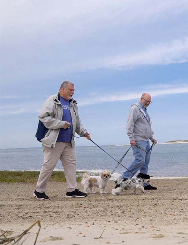 Barry and his husband walking dogs on the beach
