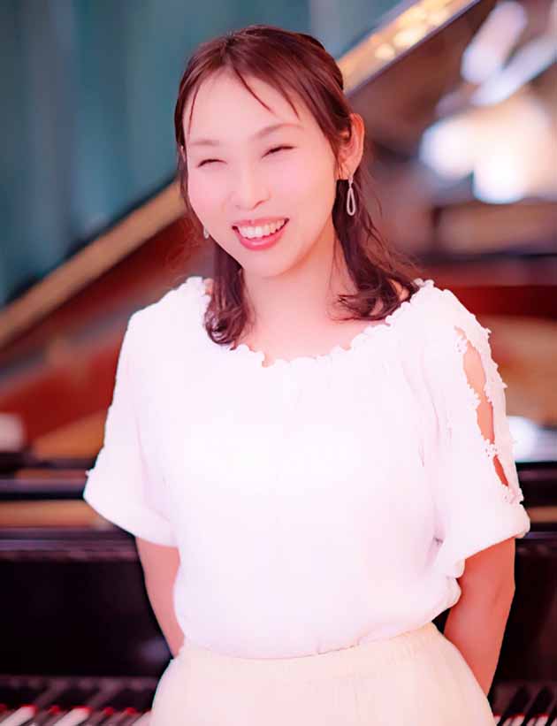 Mayu, who is living with MS, smiling in front of a piano